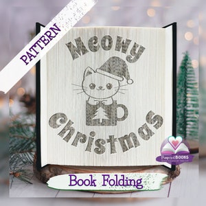 Puede incluir: Un patrón de plegado de libro para un diseño navideño con un gato que lleva un gorro de Papá Noel y sostiene una taza con un árbol de Navidad. El texto "Meowy Christmas" se muestra en el patrón.