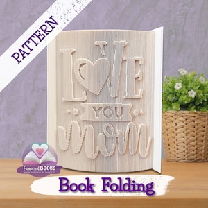 May include: A white book folded into a 3D sculpture of the words "I love you Mom" with a heart in the middle of the "love".