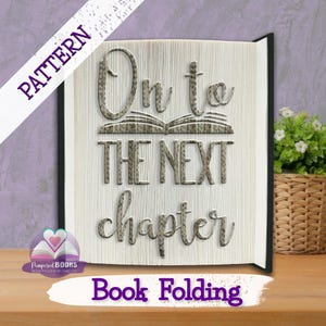 Op de afbeelding: Een decoratief boek met de woorden "On to the next chapter" uitgesneden in de pagina's. Het boek heeft een zwarte kaft en de tekst is in een decoratief lettertype. De woorden "Book Folding" staan onderaan.
