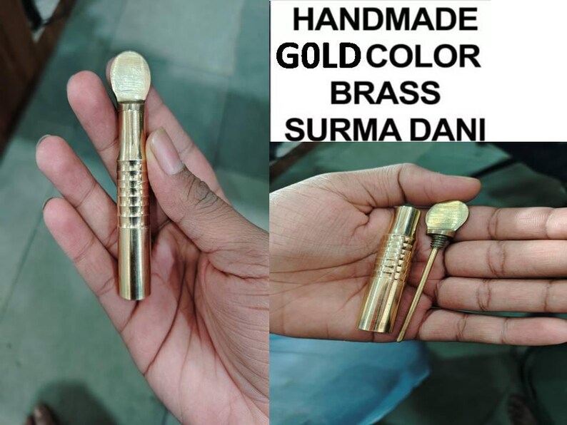 May include: A gold-colored brass surma dani, a traditional Indian eye cosmetic applicator, with a round top and a textured body. The surma dani is held in a hand.