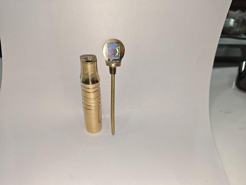 May include: A brass smoking pipe with a decorative top and a ribbed body.
