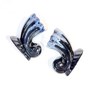 May include: A pair of black and white ceramic wall sconces with a swirl design. The sconces have a glossy finish and are perfect for adding a touch of elegance to any room.