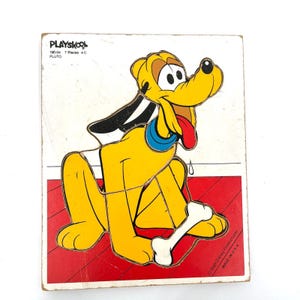 May include: Vintage Playskool Pluto puzzle. The yellow Pluto character is holding a white bone, with a red and white background. The puzzle is made of 7 pieces and is a classic Disney collectible.