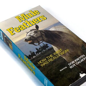 May include: A VHS tape case for the movie "Mule Feathers" featuring a gray horse with a bridle on a blue background. The text on the case reads "How the West Was Really Won!" and "Starring Don Knotts Roy Calhoun".