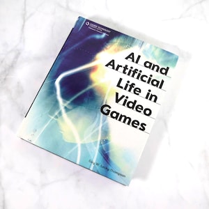 May include: A book titled "AI and Artificial Life in Video Games" by Guy W. Lecky-Thompson. The cover features a colorful abstract design with a blue, yellow, and white color scheme.