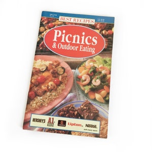 May include: A cookbook titled "Best Recipes: Picnics & Outdoor Eating" featuring images of various picnic dishes. The cover has a red oval with the title and images of food. The bottom of the cover displays logos for Hershey's, A1 Steak Sauce, Lawry's, Lipton, and Nestlé.