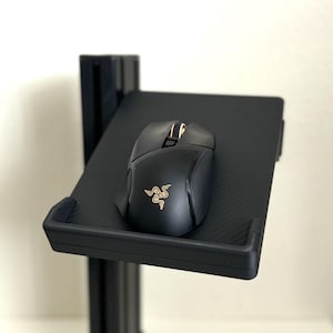以下が含まれることがあります： 黒いマウスパッドの上に黒いマウスが置かれています。マウスには金色のロゴと黒と灰色のデザインがあります。