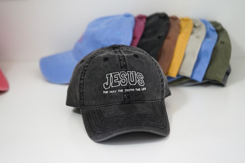 Puede incluir: Una gorra de b&eacute;isbol negra desgastada con bordado blanco que dice "JESUS THE WAY THE TRUTH THE LIFE".