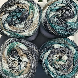 May include: Four balls of yarn in a green, blue, brown, and white color pattern. The yarn is wound into balls and ready for knitting or crocheting.