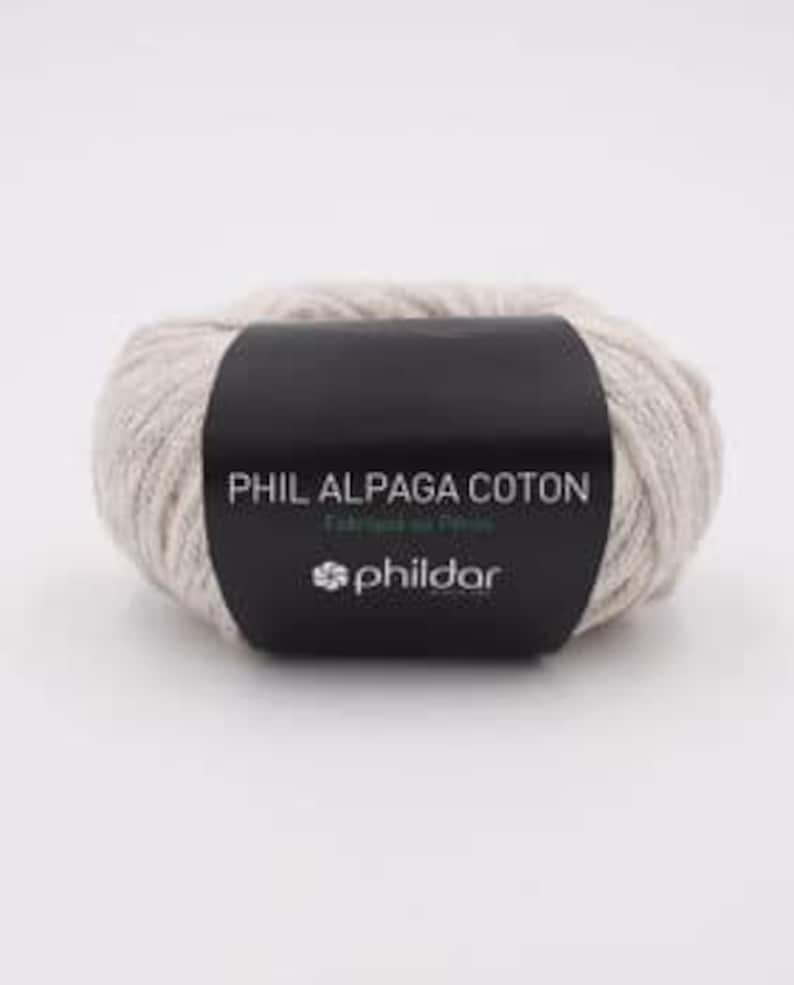 Może przedstawiać: Motka beżowej przędzy z etykietą "Phil Alpaga Coton" i logo PhilDar.