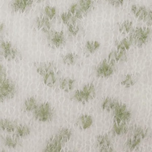 May include: A close-up view of a soft, fuzzy knit fabric featuring a white base color with an irregular, scattered pattern of light sage green spots. The material has a distinct, slightly brushed, and textured appearance with visible yarn loops.