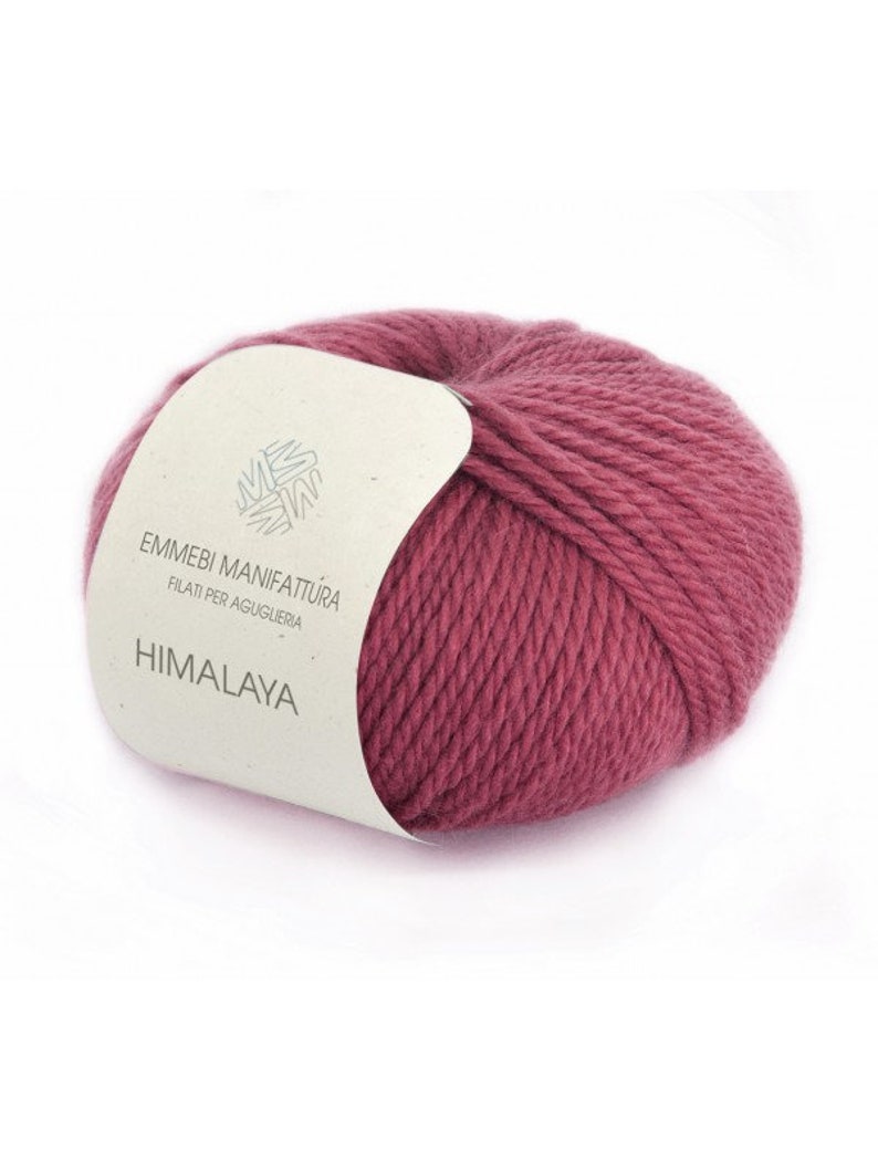 K&ouml;nnte beinhalten: Eine Kn&auml;uel rosa Wolle mit einem wei&szlig;en Etikett, auf dem "Emmebi Manifattura Filati per Agugleria Himalaya" steht.