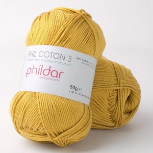 May include: Two skeins of mustard yellow cotton yarn. One skein has a white label with the text "PHIL COTON 3" and "phildar" in pink. The label also indicates the yarn is 100% cotton and weighs 50g.