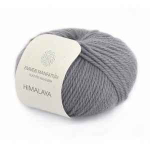 K&ouml;nnte beinhalten: Ein Kn&auml;uel grauer Wollgarn mit einem Etikett mit der Aufschrift "Emmebi Manifattura Filati per Aguglieria Himalaya".
