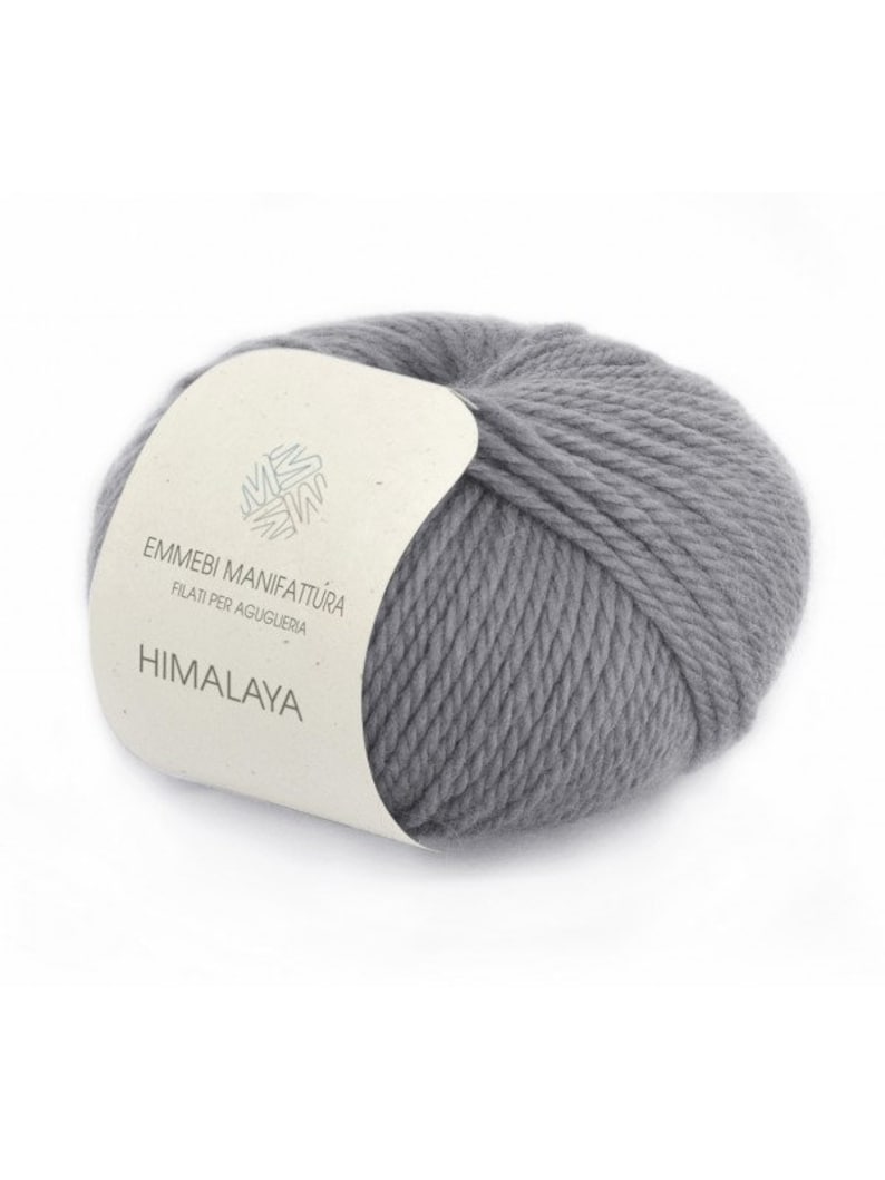 K&ouml;nnte beinhalten: Ein Kn&auml;uel grauer Wollgarn mit einem Etikett mit der Aufschrift "Emmebi Manifattura Filati per Aguglieria Himalaya".