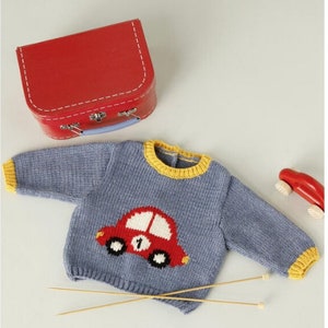 Peut inclure: Un pull en tricot bleu avec une bordure jaune et un motif de voiture rouge sur le devant. Le pull est pos&eacute; sur une surface blanche avec deux aiguilles &agrave; tricoter en bois.