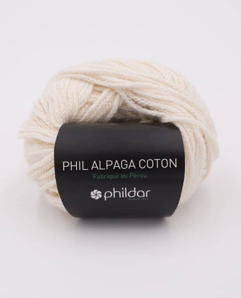 Może przedstawiać: Kulka białej wł&oacute;czki z czarną etykietą z napisem "PHIL ALPAGA COTON Fabriqu&eacute; au P&eacute;rou phildar".