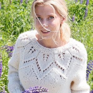May include: A cream-colored, long-sleeved, hand-knitted sweater featuring a round neckline and a decorative, openwork leaf-patterned yoke. The garment is constructed with a chunky knit texture and ribbed cuffs, showcasing a detailed stitch design.