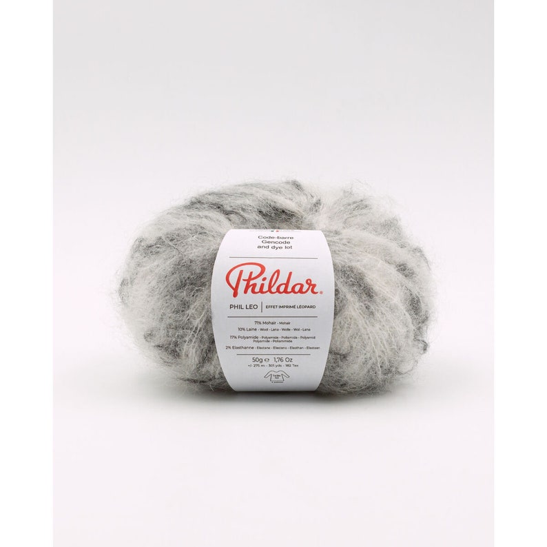 May include: A ball of fuzzy, variegated gray and white yarn with a white paper label featuring the red Phildar logo, the text PHIL LEO, and composition details including 71% mohair, 10% wool, 17% polyamide, and 2% elastane, weighing 1.76 ounces.