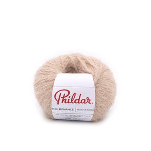 Puede incluir: Ovillo de lana beige con una etiqueta blanca. La etiqueta presenta el nombre de la marca "Phildar" en escritura roja, con "PHIL ROMANCE DOUCEUR INTENSE" impreso debajo. El ovillo pesa 50g.
