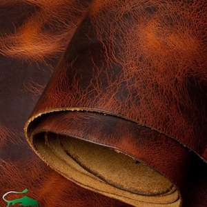 Könnte beinhalten: Nahaufnahme eines gerollten Stücks gealterten braunen Leders. Das Leder hat eine strukturierte Oberfläche mit einem Netzwerk feiner Linien und einem helleren braunen Innenraum. Die Kanten des Leders sind sichtbar und zeigen die Schichten.