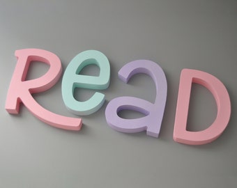 Könnte beinhalten: Das Wort "READ" in bunten, dreidimensionalen Buchstaben. Die Buchstaben sind rosa, hellblau, lila und rosa.