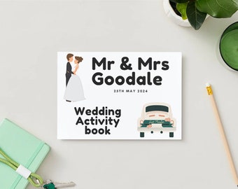 Könnte beinhalten: Ein weißes Hochzeits-Aktivitätsbuch mit einer Cartoon-Illustration eines Brautpaares und einem Oldtimer mit einem Schild "Just Married". Der Text auf dem Cover lautet "Mr. & Mrs. Goodale 25th May 2024 Wedding Activity Book".
