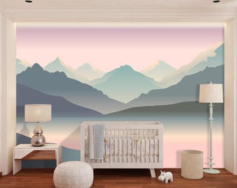 May include: A wall mural featuring a layered mountain landscape in shades of blue, gray, and teal against a soft pink sky. The scene includes a calm body of water reflecting the mountains, creating a serene, panoramic view across the entire wall.