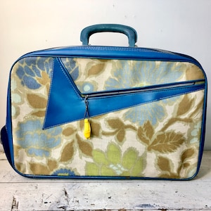 Small vintage suitcase with blue vinyl and a floral pattern; bonus Ski-doo promo charm!