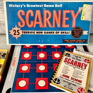 May include: A vintage board game box with the title "SCARNEY" in red and white letters. The box features a blue background with a white star and the text "25 TERRIFIC NEW GAMES OF SKILL!" The box also includes a smaller box with the text "SCARNEY" and a booklet with the title "SCARNEY" and the text "A NEW ERA IN SKILL GAMES".