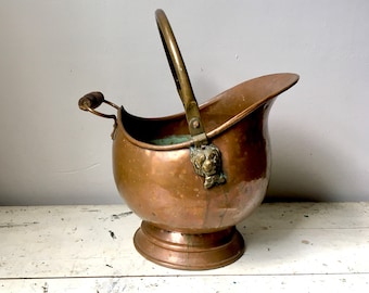 Antiguo scuttle de carbón de cobre con cabezas de león; forjado a mano
