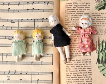 Collection of four vintage bisque Charlotte dolls with handmade dresses