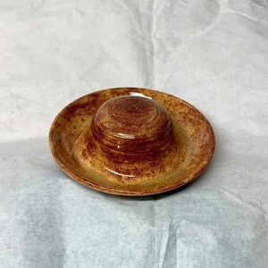 May include: A brown and tan ceramic dish with a smaller, matching bowl inside. The dish has a speckled glaze.