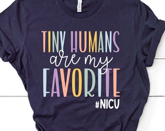 May include: A navy blue t-shirt with the text "Tiny Humans are my Favourite #NICU" in rainbow colours.