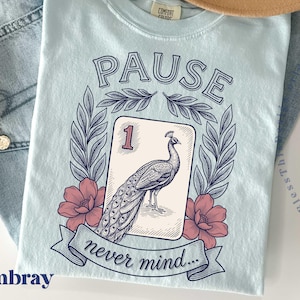 A unisex Comfort Colors t-shirt featuring a retro floral peacock mahjong tile graphic and the funny phrase Pause Nevermind.
