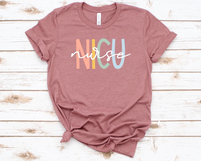May include: A mauve t-shirt with the text "NICU nurse" in rainbow colors.