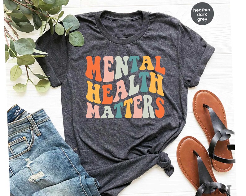 May include: A heather dark grey t-shirt with the text "Mental Health Matters" in colorful retro-style lettering.