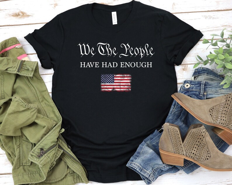 May include: Black t-shirt with the text "We The People Have Had Enough" in white lettering. A distressed American flag graphic is below the text.