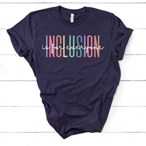 May include: A navy blue t-shirt with the text "Inclusion is for everyone" in rainbow colors.