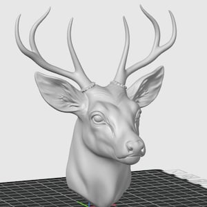 Puede incluir: Una escultura en escala de grises, renderizada en 3D, de una cabeza de ciervo. El ciervo tiene grandes astas detalladas, orejas prominentes y una estructura facial realista. La escultura está sobre un fondo liso, con una superficie cuadriculada debajo.