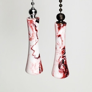 May include: Two white and red marbled fan pull chains with silver and bronze finials.