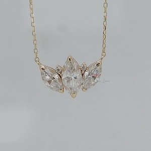 May include: A gold chain necklace with a pendant featuring three marquise-shaped diamonds set in a cluster.
