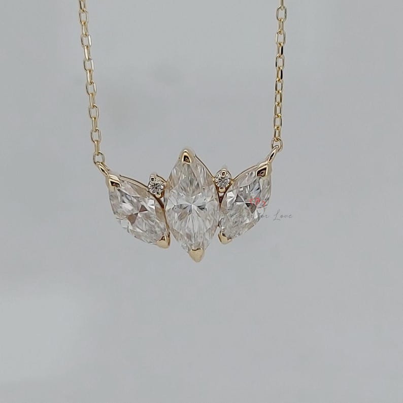 May include: A gold chain necklace with a pendant featuring three marquise-shaped diamonds set in a cluster.
