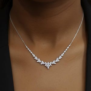 Puede incluir: Un delicado collar de plata con un dise&ntilde;o en forma de hojas. El collar presenta una serie de peque&ntilde;as piedras brillantes dispuestas en un patr&oacute;n sim&eacute;trico. El dise&ntilde;o central es un grupo de piedras, con una fina cadena.
