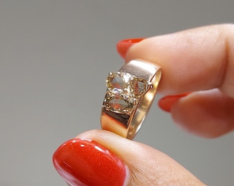 May include: A gold ring with a large, three-stone, yellow diamond setting.