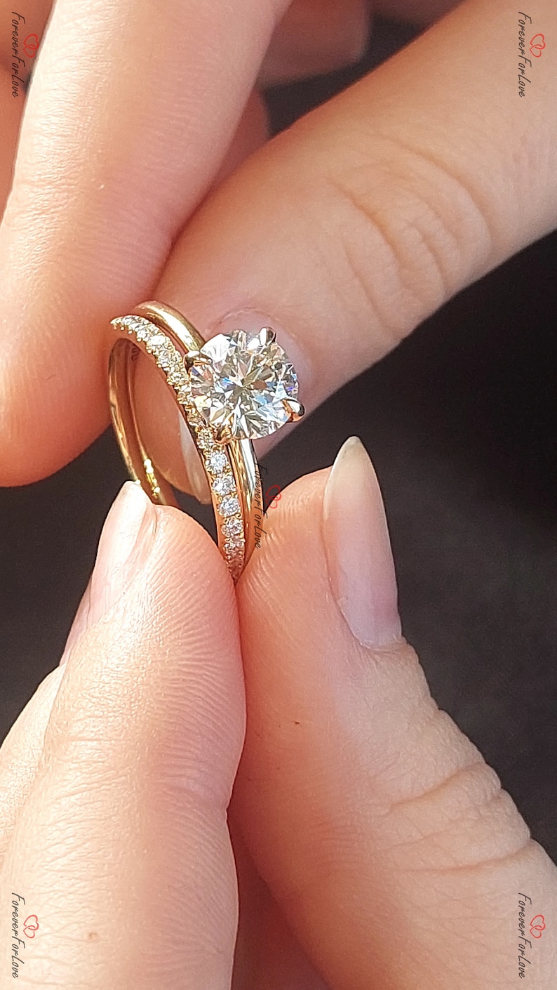 May include: A close-up of a gold wedding band set with a large, round, brilliant-cut diamond solitaire engagement ring. The band is set with smaller diamonds.