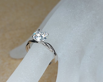 May include: A silver ring with a twisted band and a large, clear, round gemstone.