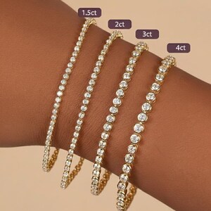 Puede incluir: Se muestran cuatro pulseras de tenis doradas con piedras preciosas redondas y transparentes. Cada pulsera est&aacute; etiquetada con su peso en quilates: 1,5 ct, 2 ct, 3 ct y 4 ct. Las pulseras se muestran en una mu&ntilde;eca, mostrando los diferentes tama&ntilde;os.