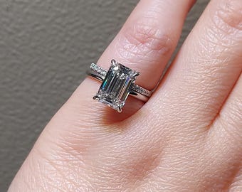 May include: A silver engagement ring with a large emerald cut diamond and a diamond band.