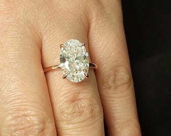 May include: A rose gold engagement ring featuring a large oval-shaped diamond.